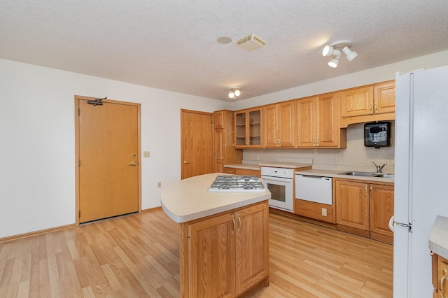 kitchen with white appliances, light hardwood / wood-style flooring, a kitchen island, and a textured ceiling