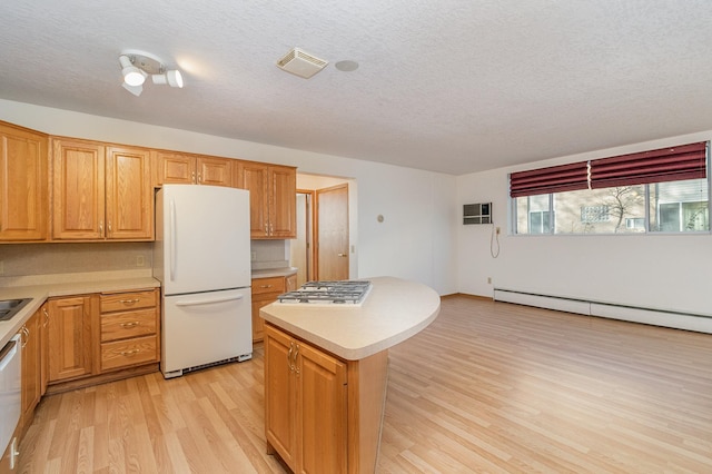 kitchen featuring white appliances, a center island, a textured ceiling, and light hardwood / wood-style flooring