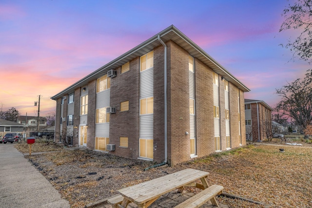 property exterior at dusk featuring a wall mounted air conditioner