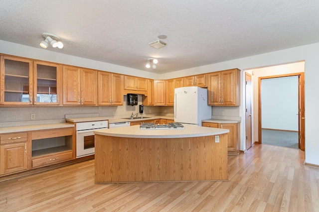 kitchen with sink, white appliances, light hardwood / wood-style floors, and a textured ceiling