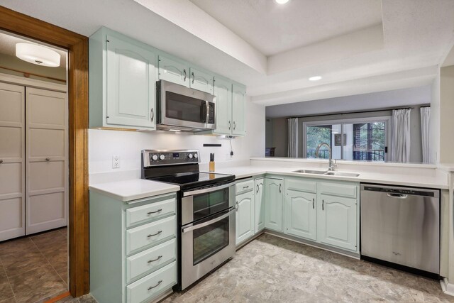 kitchen with appliances with stainless steel finishes, a raised ceiling, and sink