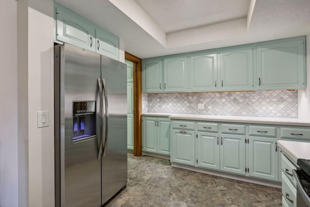 kitchen featuring a raised ceiling, appliances with stainless steel finishes, green cabinets, and tasteful backsplash