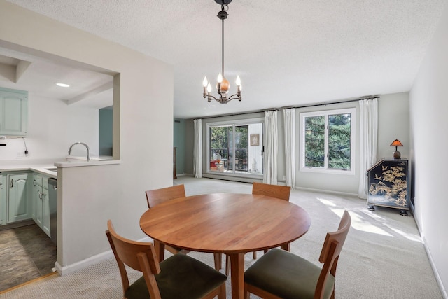 carpeted dining space with sink, an inviting chandelier, and a textured ceiling