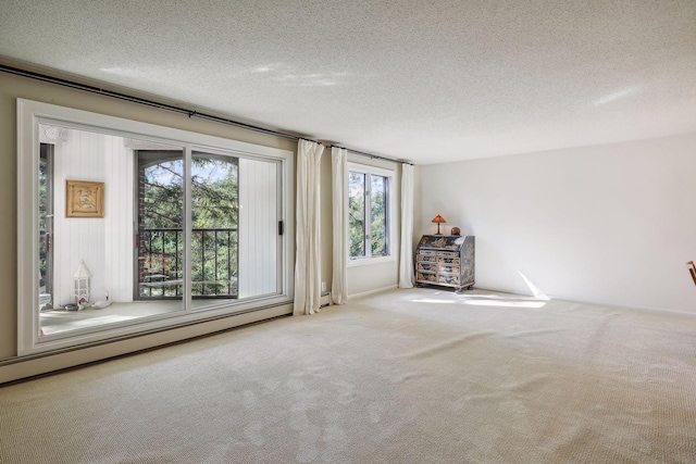 carpeted empty room with a textured ceiling and baseboard heating