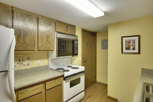 kitchen with light wood-type flooring, white appliances, and a textured ceiling