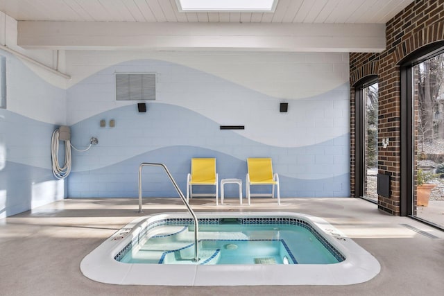 view of pool featuring a skylight and an indoor hot tub