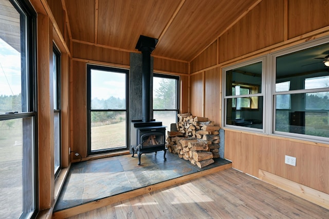 unfurnished sunroom with a wood stove, wooden ceiling, and vaulted ceiling