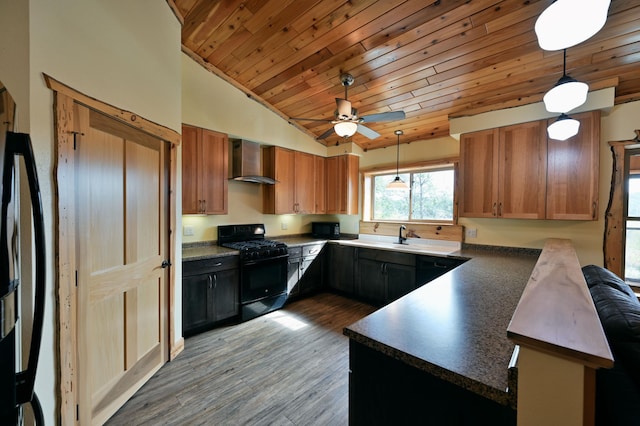 kitchen with dark countertops, wall chimney range hood, a peninsula, black appliances, and pendant lighting