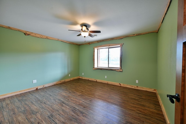 empty room featuring dark wood finished floors, baseboards, and ceiling fan