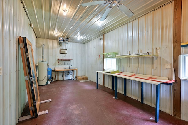 below grade area featuring water heater, ceiling fan, a workshop area, and metal wall