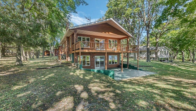 back of property featuring a yard, a wooden deck, and a patio area