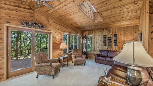 carpeted living room with wood ceiling, high vaulted ceiling, wood walls, ceiling fan, and a skylight