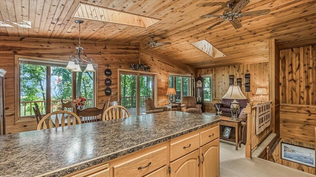 kitchen with ceiling fan, vaulted ceiling with skylight, plenty of natural light, and wooden ceiling