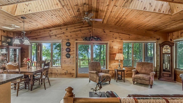 living room featuring a wealth of natural light, ceiling fan, wooden ceiling, and wooden walls