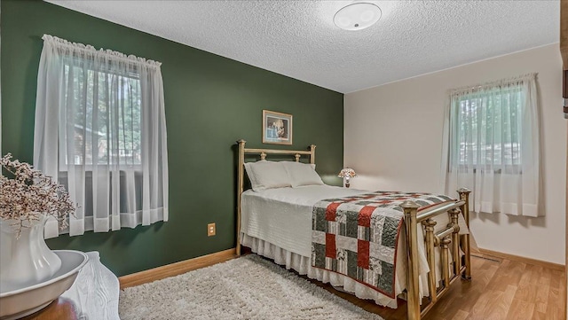 bedroom featuring multiple windows, a textured ceiling, and hardwood / wood-style flooring