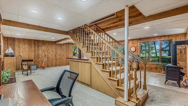 office space featuring a wood stove, light colored carpet, and wooden walls