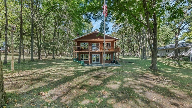 rear view of house with a wooden deck, a yard, and a patio