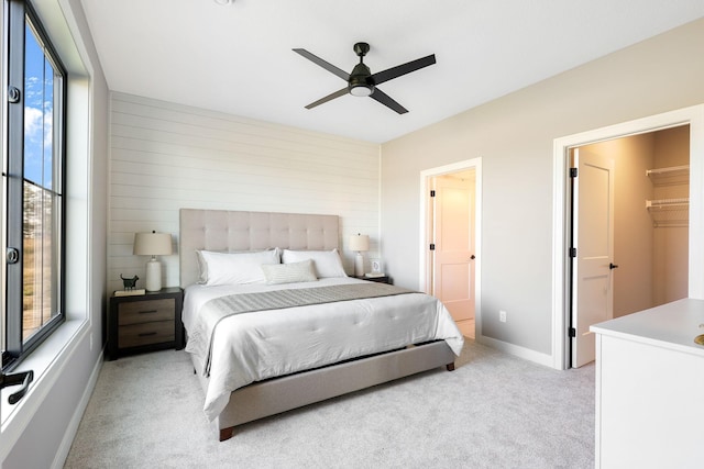 carpeted bedroom with ceiling fan, a walk in closet, a closet, and wooden walls