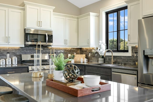 kitchen with sink, appliances with stainless steel finishes, white cabinetry, and tasteful backsplash