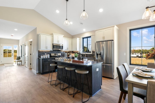 kitchen featuring appliances with stainless steel finishes, wood-type flooring, a center island, and a kitchen breakfast bar