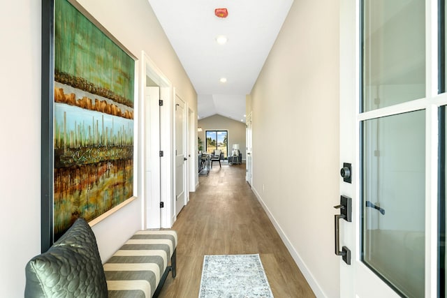 corridor with vaulted ceiling and wood-type flooring