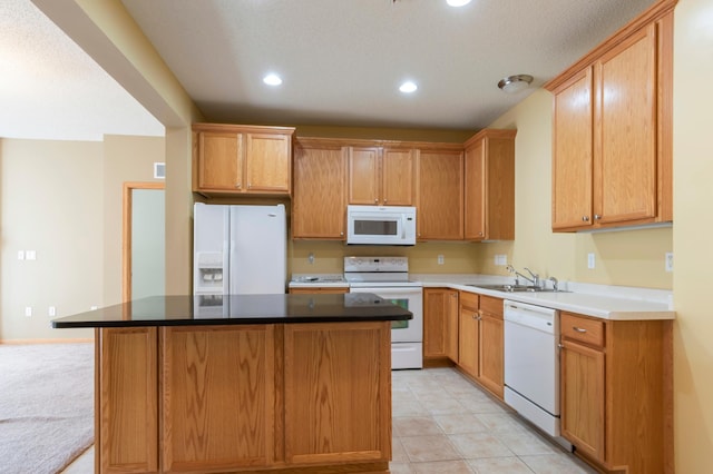 kitchen with white appliances, a center island, light tile patterned floors, and sink