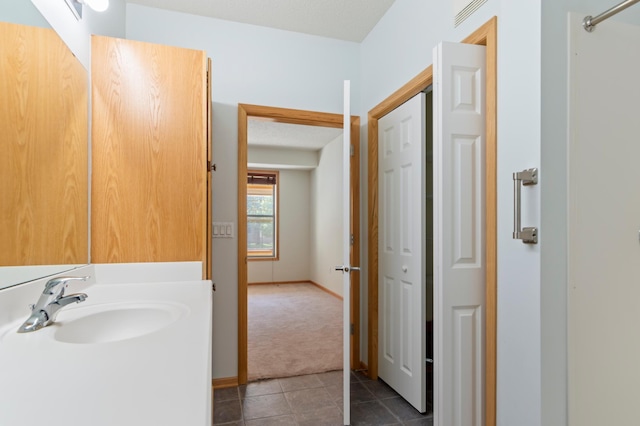 bathroom featuring a textured ceiling, tile patterned flooring, and vanity