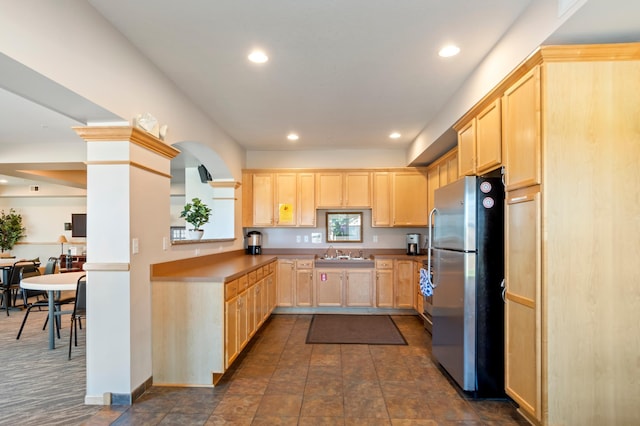 kitchen with light brown cabinets, stainless steel fridge, and sink