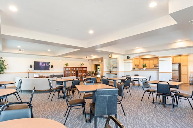 carpeted dining space with a tray ceiling