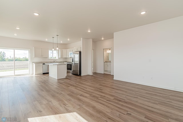 unfurnished living room featuring sink and light hardwood / wood-style floors