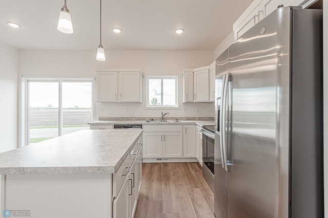 kitchen with light hardwood / wood-style flooring, appliances with stainless steel finishes, hanging light fixtures, and a kitchen island