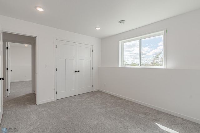 unfurnished bedroom with a closet and light colored carpet