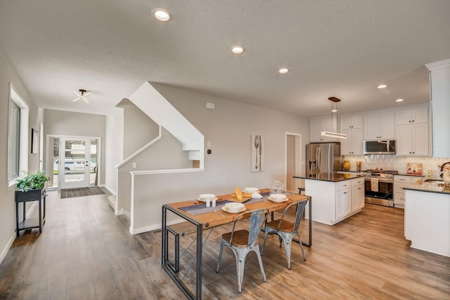 dining space with sink, a textured ceiling, and light hardwood / wood-style flooring