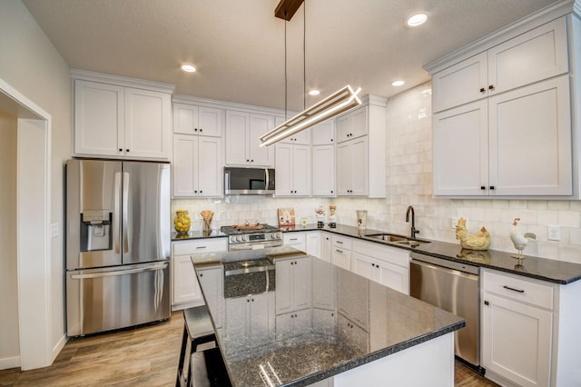 kitchen featuring a center island, dark stone countertops, stainless steel appliances, and light hardwood / wood-style flooring