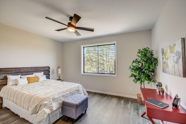 bedroom featuring dark hardwood / wood-style flooring, ceiling fan, and a textured ceiling