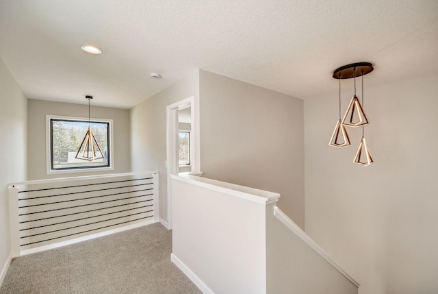 hallway featuring a textured ceiling, carpet, and radiator heating unit