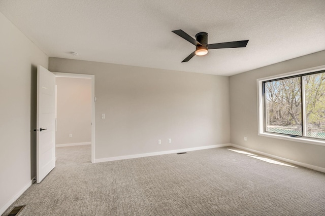 carpeted empty room featuring ceiling fan and a textured ceiling