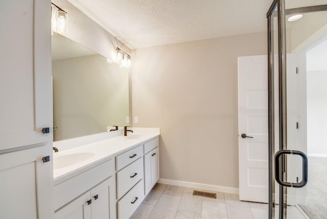 bathroom with vanity, a textured ceiling, and walk in shower