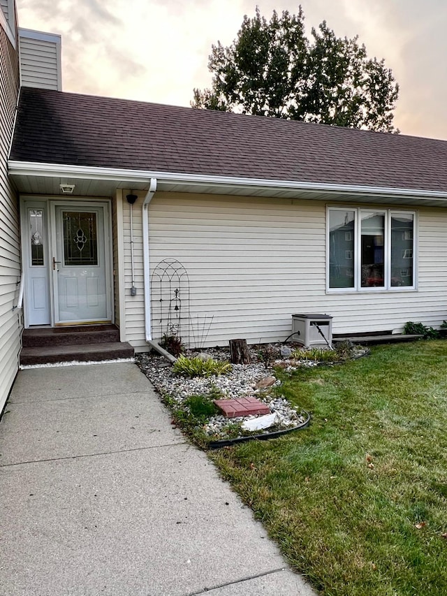 exterior entry at dusk featuring a lawn