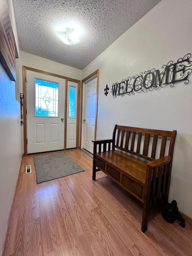 foyer entrance with light hardwood / wood-style flooring and a textured ceiling