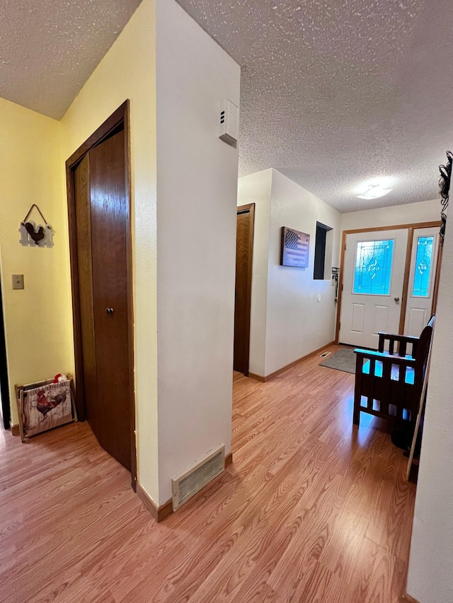 hall with light hardwood / wood-style floors and a textured ceiling