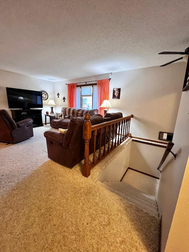 carpeted living room featuring ceiling fan and a textured ceiling