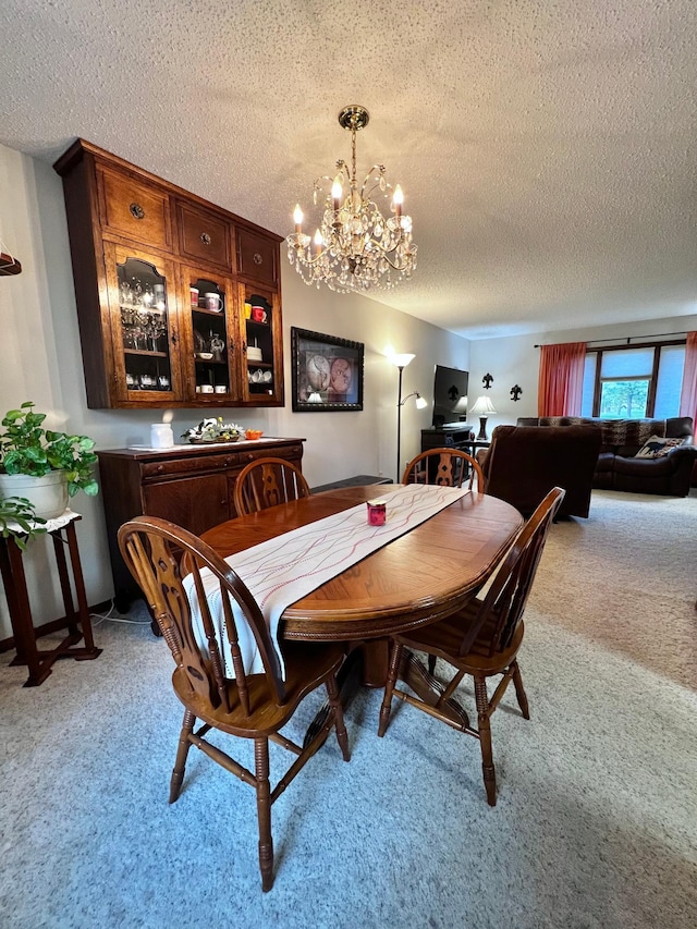 dining room with a textured ceiling, light colored carpet, and an inviting chandelier