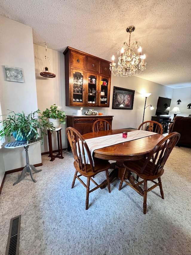 carpeted dining area with a textured ceiling and an inviting chandelier