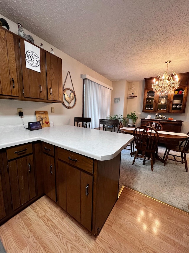 kitchen featuring kitchen peninsula, a textured ceiling, and light hardwood / wood-style flooring