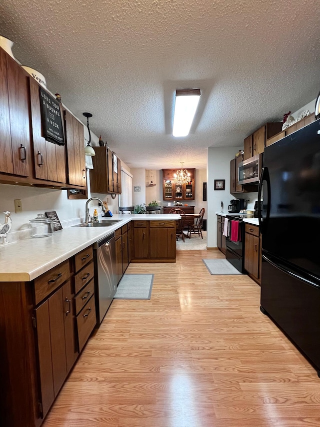 kitchen featuring a chandelier, decorative light fixtures, a textured ceiling, black appliances, and light wood-type flooring