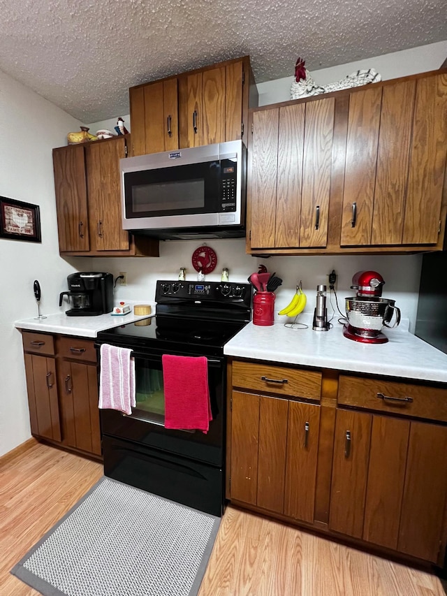 kitchen featuring electric range, light hardwood / wood-style flooring, and a textured ceiling