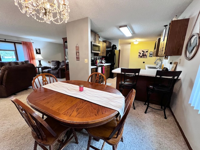 carpeted dining room with sink, a chandelier, and a textured ceiling