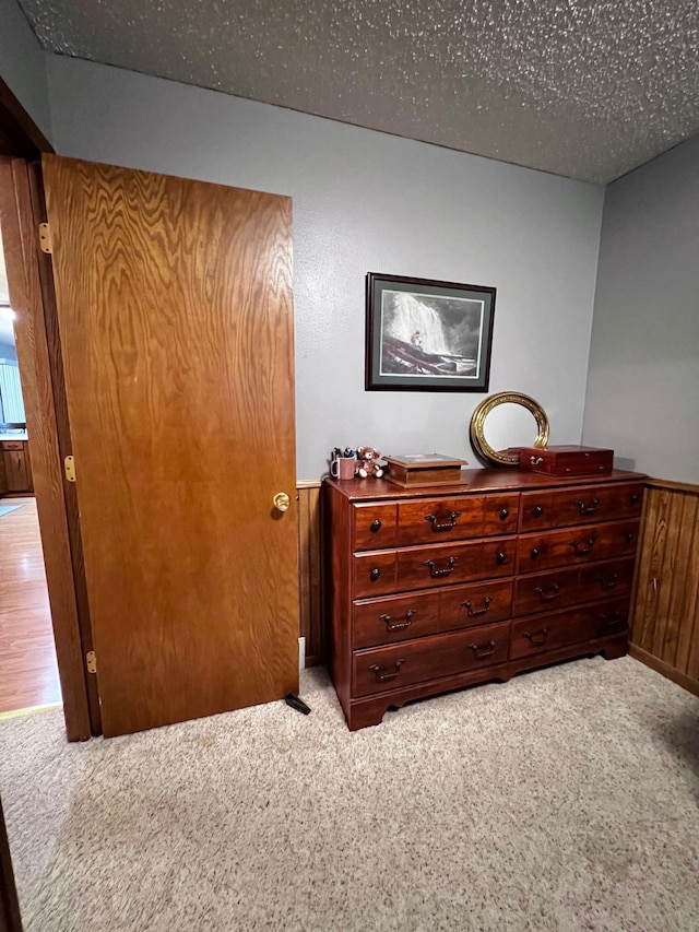 carpeted bedroom with wooden walls and a textured ceiling