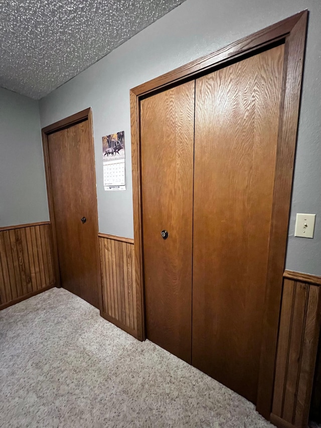 interior space featuring a textured ceiling, a closet, and wooden walls